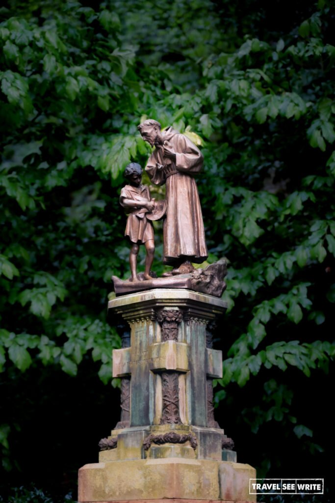 A bronze statue of Saint Francis of Assisi interacting with a young boy at Eremo delle Carceri 