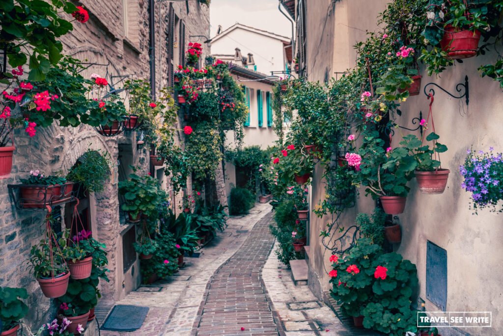 Bursting with colourful flowers, the winding stone alleyways of Spello, Italy, showcase the breathtaking, fairy-tale charm of this historic medieval town.